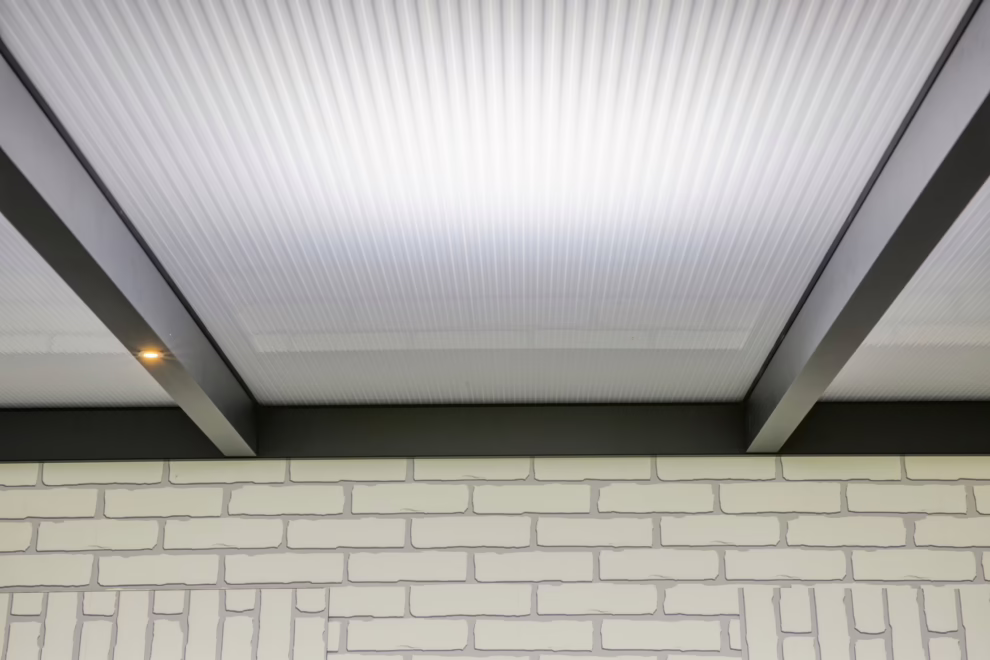 Onderzijde van een overkapping met polycarbonaat dakplaten en aluminium liggers