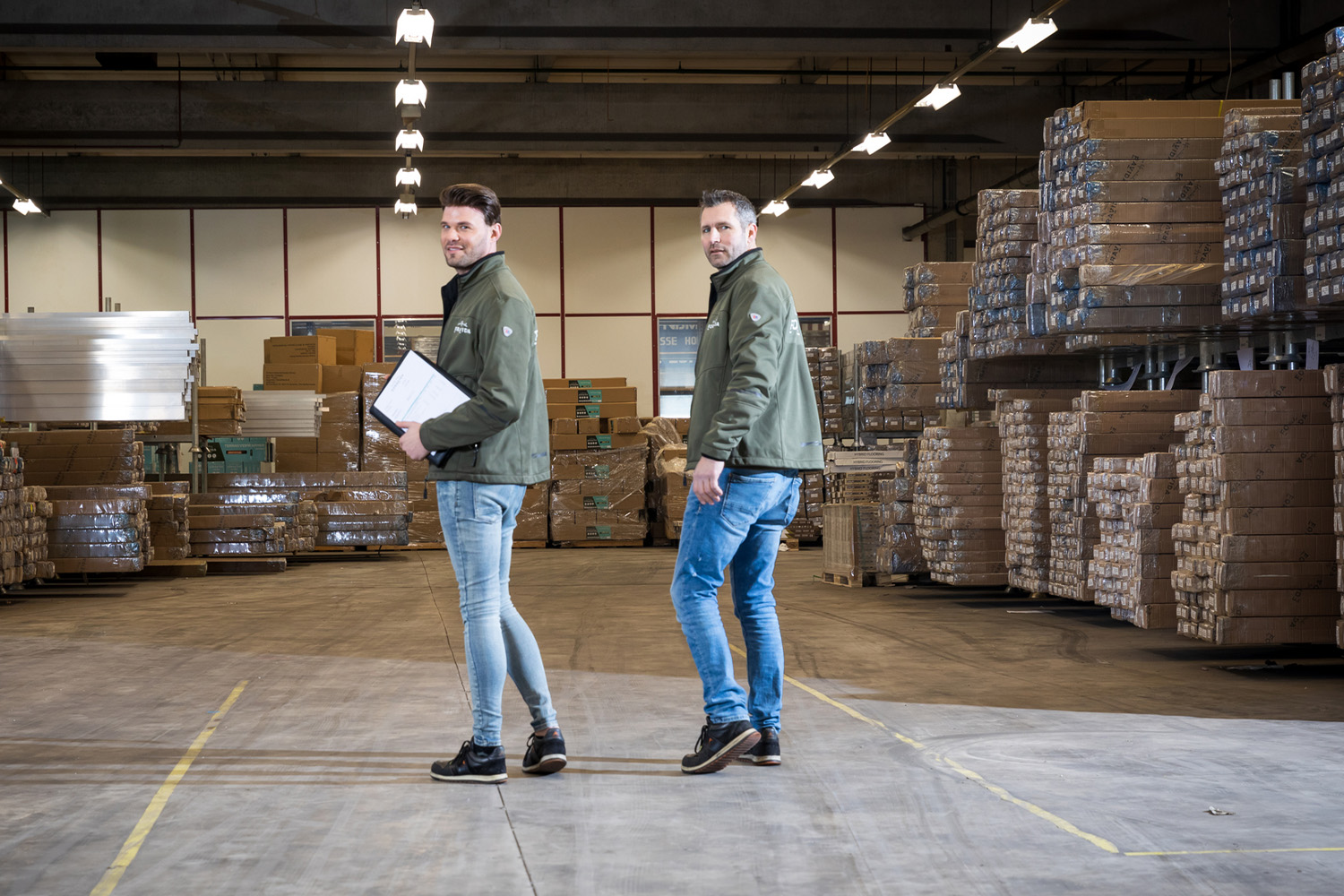 Twee ForaVida magazijnmedewerkers tussen ingepakte bouwpakketten in het magazijn